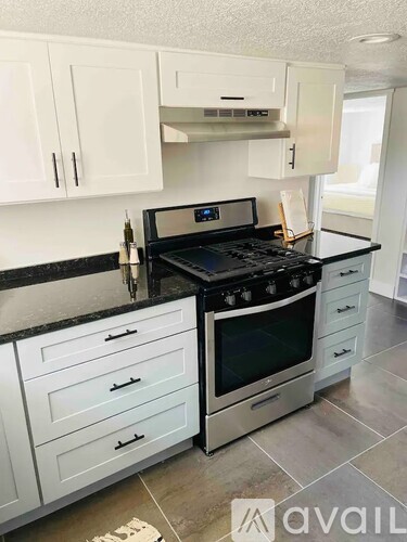 A kitchen with a black stove top oven and white cabinets.
