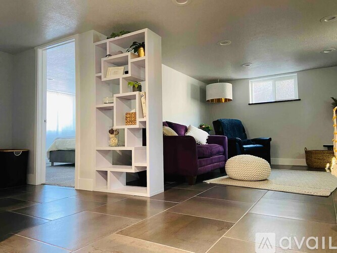 A living room with a purple couch and a white shelf.