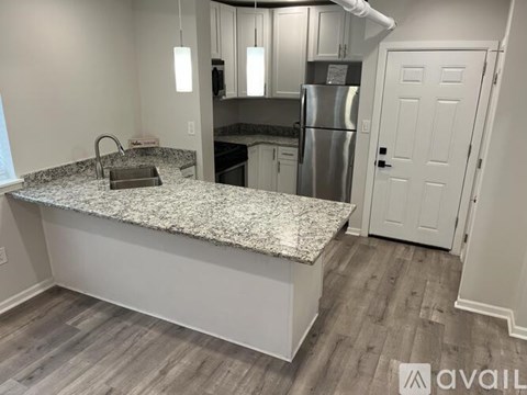A kitchen with a granite countertop and a refrigerator in the background.
