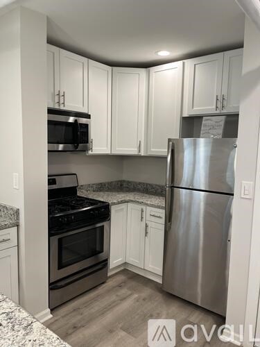 A kitchen with a stainless steel refrigerator, microwave, oven, and cabinets.