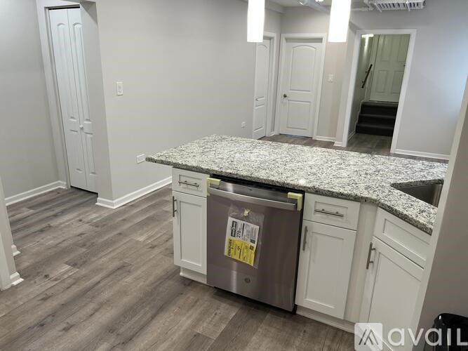 A kitchen with a granite countertop and a dishwasher in the middle.