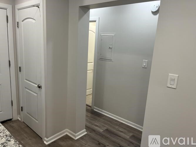A hallway with a white door and a light switch on the wall.