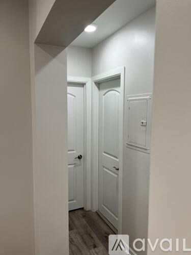 A hallway with white doors and a wooden floor.