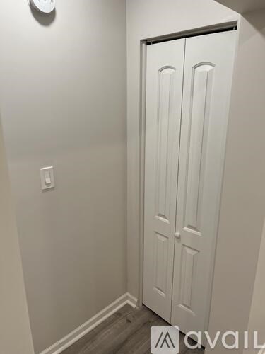 A white door in a room with a clock on the wall.