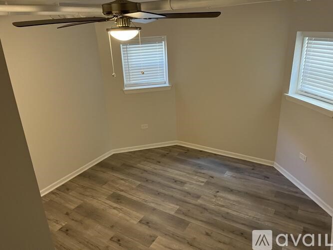 A room with a ceiling fan and wooden flooring.
