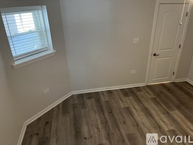 A room with wooden flooring and a window with blinds.