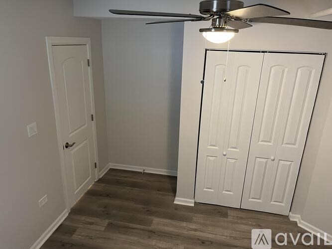 A room with a ceiling fan and a white door.
