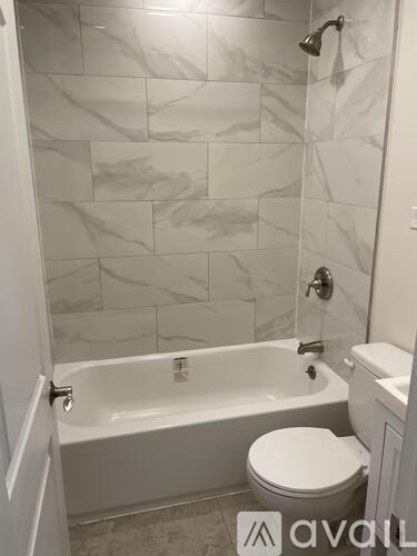 A bathroom with a white tub, toilet and tiles.