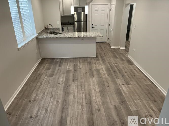 A kitchen with a granite countertop and wooden flooring.