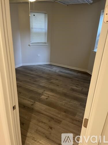 A room with wooden flooring and a window with blinds.