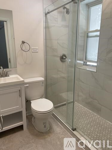 A white toilet sits in a bathroom next to a sink and a glass shower door.