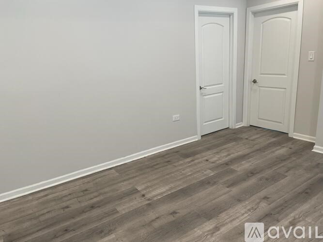 A room with two white doors and wooden flooring.