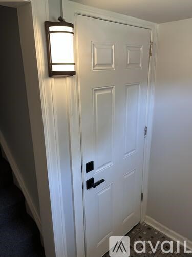 A white door with a black handle and a light on the wall.