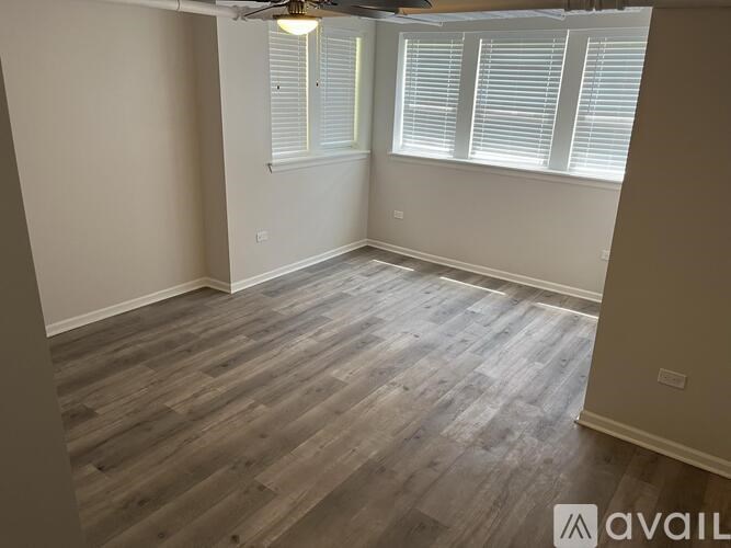 A room with wooden flooring and a window with blinds.
