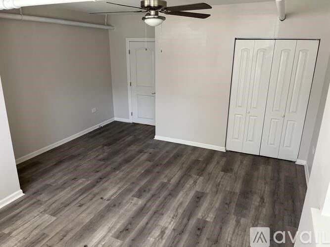 A room with a ceiling fan and wood flooring.