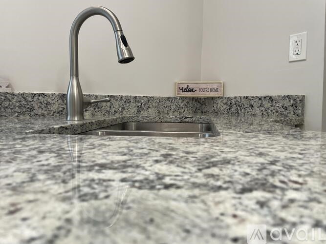 A kitchen sink with a granite countertop and a chrome faucet.