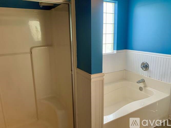 A white bathtub with a silver faucet is in a bathroom with blue walls.