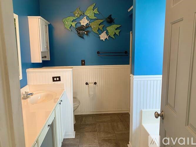 A bathroom with blue walls and a white sink and toilet.