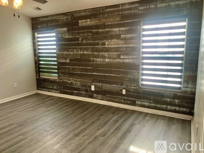 A room with wooden flooring and a wooden wall with a window.