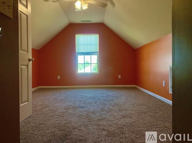A room with a carpeted floor and a window letting in light.