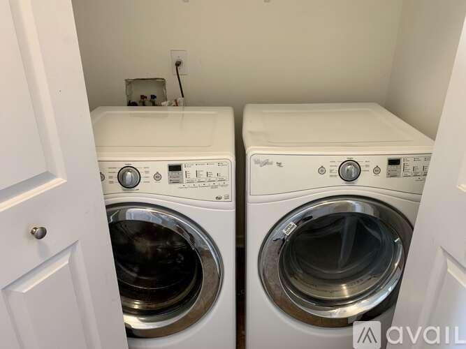 Two white front load washing machines in a small laundry room.
