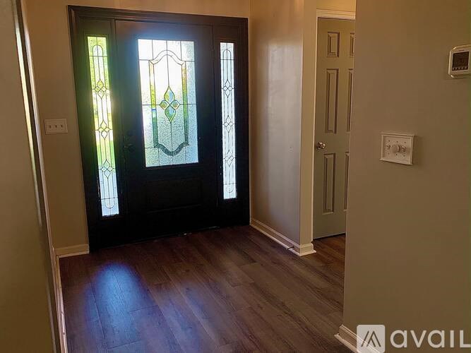 A room with a wooden floor and a glass door with a stained glass window.
