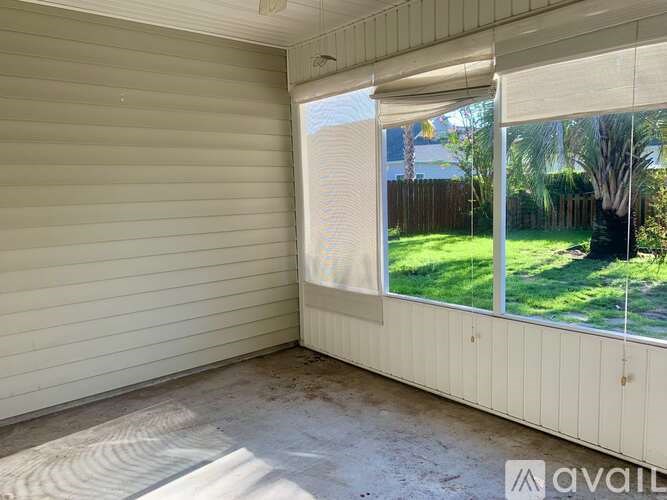 A room with a window overlooking a green lawn.