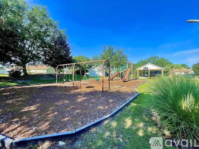 A playground with a swing set and a playhouse in the background.