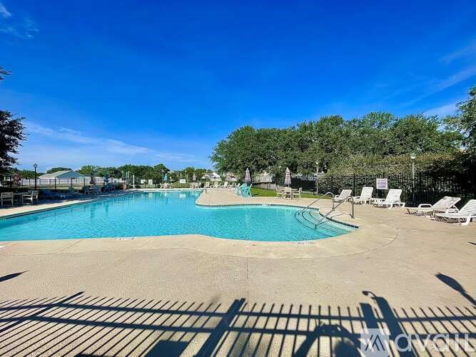 A large outdoor swimming pool surrounded by trees and lounge chairs.