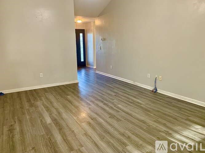 A room with wooden flooring and a door at the end.