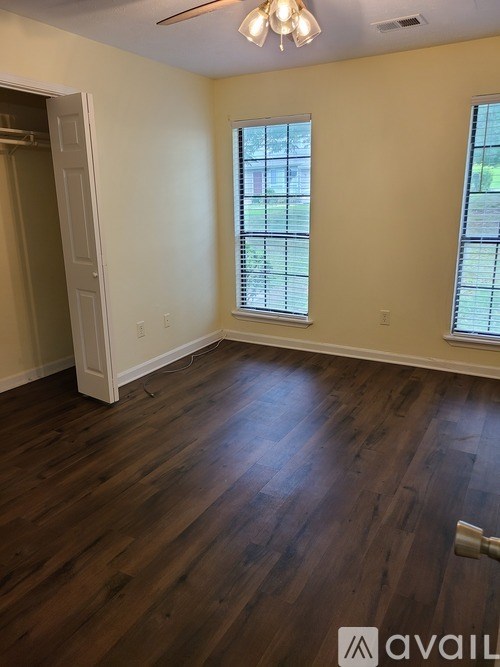 A room with wooden floors and two windows.