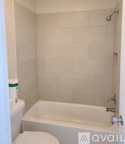 A white tiled bathroom with a toilet, tub, and shower.