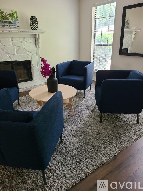 A living room with a fireplace and blue chairs.
