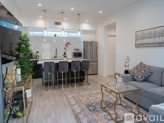 A modern kitchen with a bar area and a grey sofa.