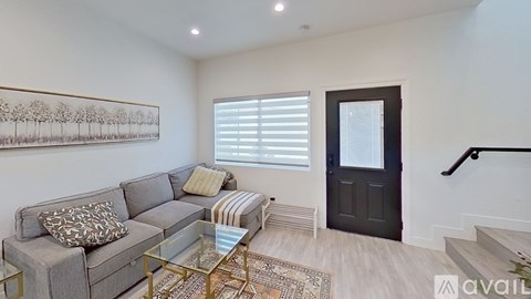 A living room with a grey couch and a glass coffee table.