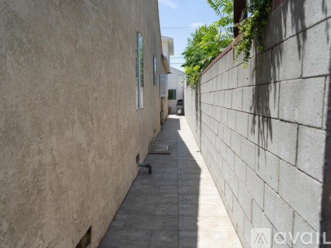 A narrow alley with a wall on one side and a building on the other.