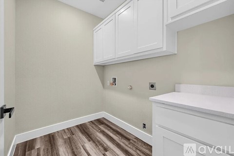 A kitchen with white cabinets and a wooden floor.