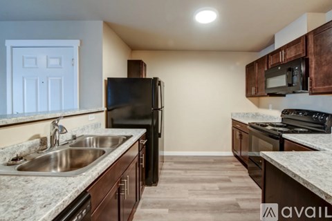 A kitchen with a black refrigerator, microwave, and stove.