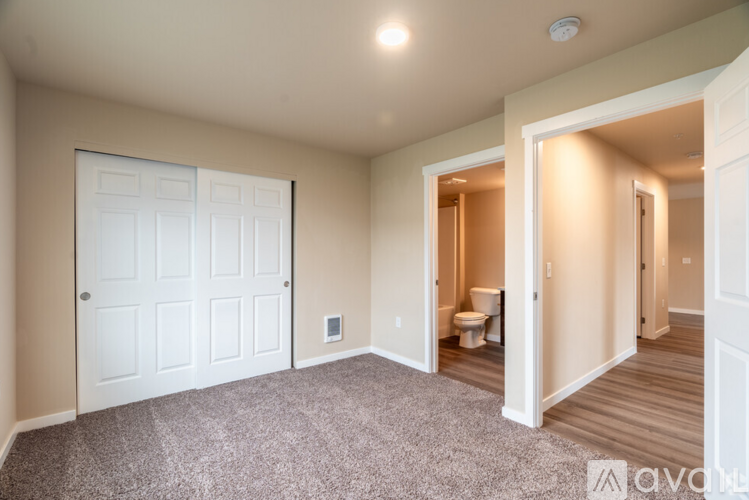 A room with a white door and a toilet in the other room.