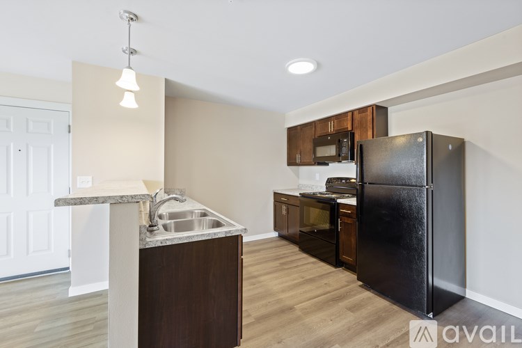 A kitchen with a black fridge and wooden cabinets.