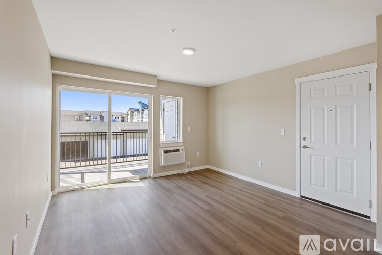A spacious room with wooden floors and a large window overlooking a balcony.