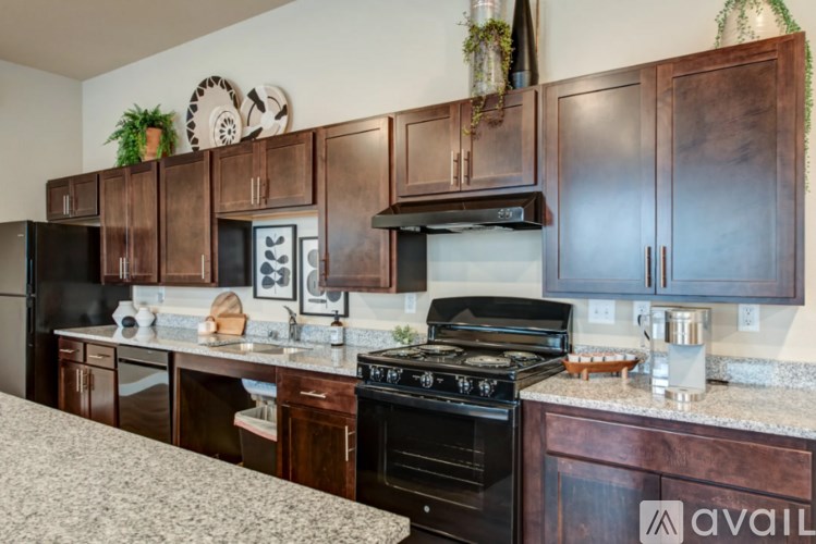 A kitchen with dark wood cabinets and black appliances.