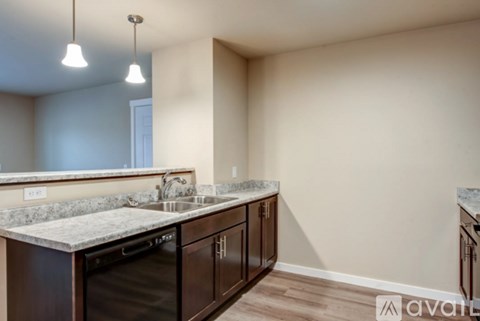 A kitchen with a granite countertop and dark brown cabinets.