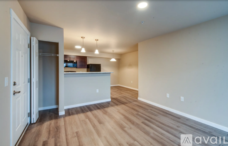 A room with wooden flooring and a white wall with a door on the left side.