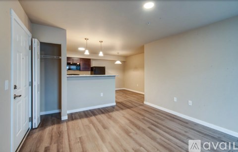 A room with wooden flooring and a white wall with a door on the left side.