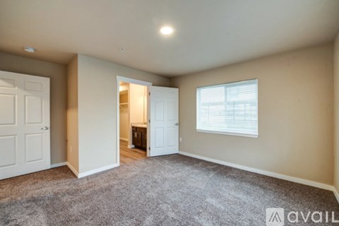 A room with a carpeted floor and a window with blinds.