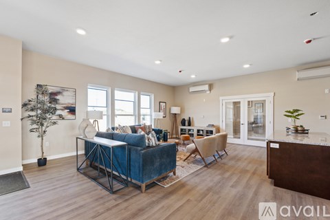 A living room with a blue velvet sofa and a wooden floor.