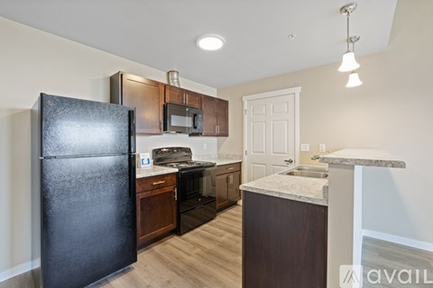 A kitchen with a black fridge and wooden cabinets.