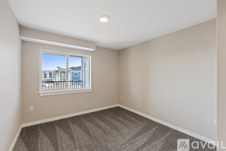 A room with a window overlooking a balcony with chairs.