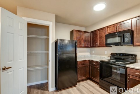 A kitchen with black appliances and wooden cabinets.